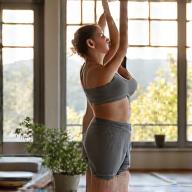 Person stretching gracefully in a beautifully designed home gym with natural light, representing movement and fitness habits.